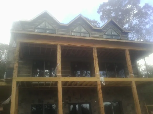 Dormers and porch framing on a large log home under construction — Roof Coating work by our crew in Okeechobee