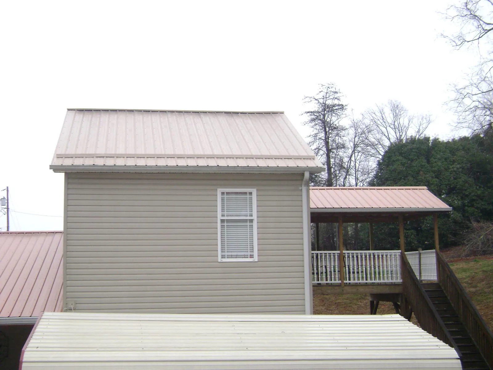 Tan metal roofs on a two story addition and attached porch, from a Roof Replacement job in Okeechobee