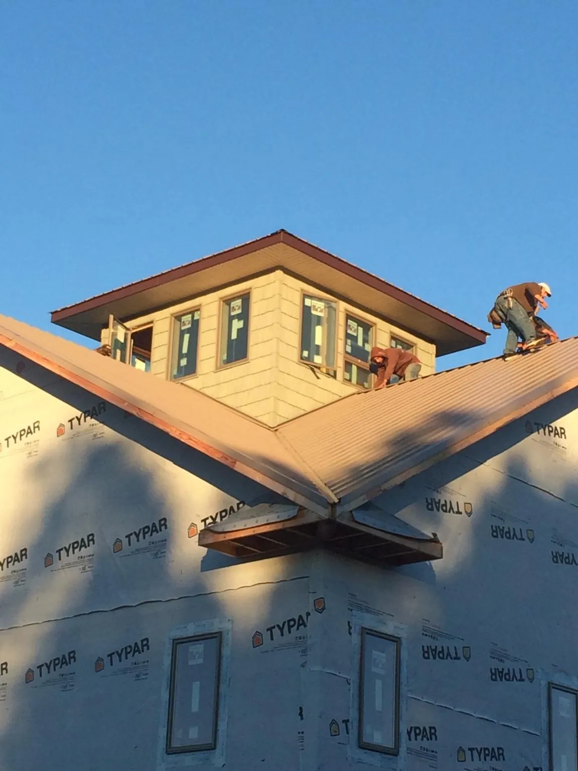 Roofers working around a rooftop cupola on a new metal roof at sunset — Roof Waterproofing in Okeechobee by Roofing Brothers
